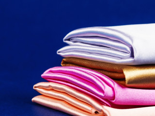 rolls of silk of different colors folded stack. colorful fabric silk stack background.