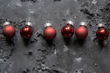 rote Christbaumkugeln zu Weihnachten auf dunklem strukturiertem Untergrund