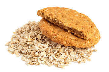 One and half crunchy oat and wholemeal biscuits on a heap of oats isolated on white.