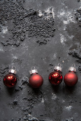 rote Christbaumkugeln zu Weihnachten auf dunklem strukturiertem Untergrund