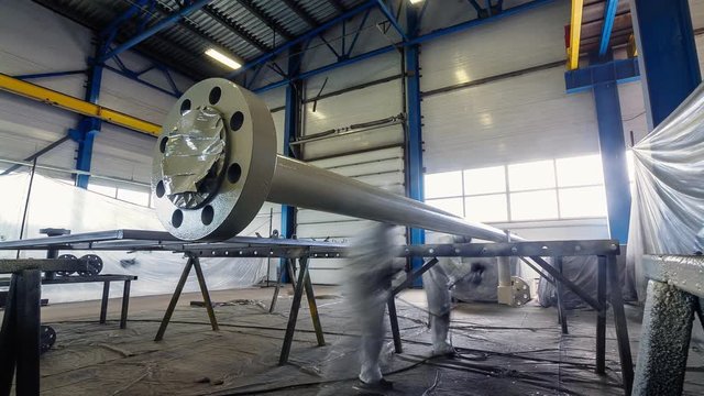 worker paints large pipe with sprayer in workshop timelapse