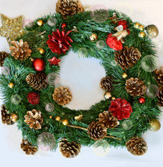 Fototapeta na wymiar Green, red and golden Christmas wreath with transparent Christmas balls and pine cones