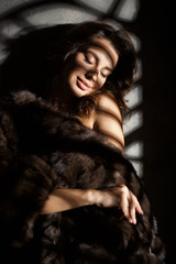 very beautiful girl in a fur coat with clean skin and cool makeup and long hair