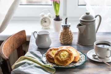 Cheesecake rolls for Breakfast on a wooden table by the window with a cat