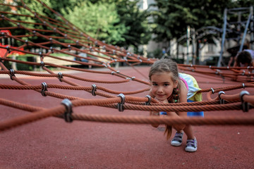 Happy girl having a rest on the playground in local park during her travelling