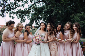Bride with bridesmaids. Girl bride with her friends in elegant dresses. Bride with bridesmaids on the park on the wedding day. Happy girls at their best friend's wedding. 