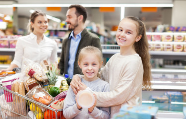 Man with wife and children holding purchases in supermarket