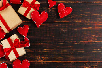 Preparation for Valentine's Day. Red hearts and craft gifts on wooden background. Copy space.