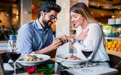 Young man surprised his girlfriend with engagement ring in the restaurant. Lifestyle, love, relationships, food concept