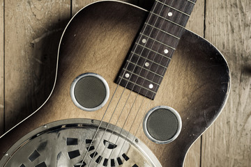 A detail of a vintage guitar on a wooden background