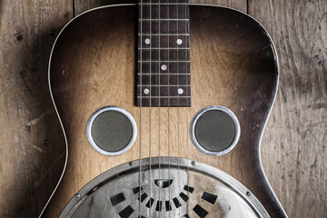 A detail of a vintage guitar on a wooden background