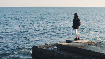 Young beautiful woman walks and enjoys the sea on a warm winter day. Slow motion