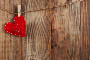 The concept of the preparation for Valentine's Day. Red hearts are held by clothespins on jute rope, on a dark wooden background. Copy space.