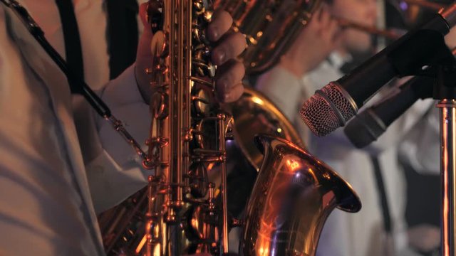Close-up of a saxophonist playing saxophone with musicians in the background