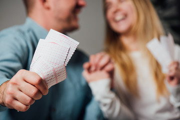 cropped view of happy man and woman holding hands while holding lottery tickets - obrazy, fototapety, plakaty