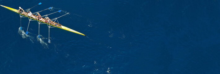 Aerial drone ultra wide photo of team of fit women practising in sport canoe in deep blue open ocean sea