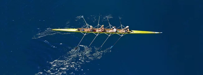 Fototapeten Aerial drone ultra wide photo of team of fit women practising in sport canoe in deep blue open ocean sea © aerial-drone