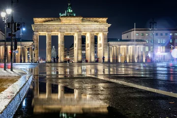 Das Brandenburger Tor in Berlin bei Nacht und Regen im Winter mit Reflektionen im Regenwasser © moofushi