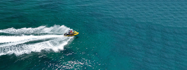 Aerial photo of jet ski with couple cruising in high speed in Caribbean tropical crystal clear...