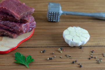 head of garlic hammer for a chop and a piece of meat on wooden background, concept of cooking steak