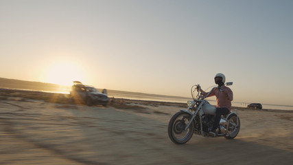 Obraz premium Motorcyclist driving his motorcycle on the dirt road during sunset