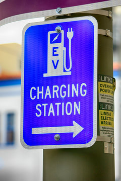 Blue and white information sign pointing to an EV (Electric Vehicle) charging Station.