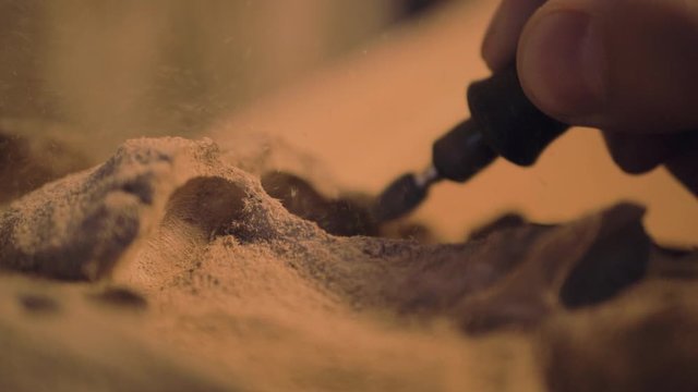 Hand using tool equipment carving wood art shavings dust flying out slow motion close up detail
