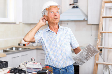 Puzzled worker checking plaster work indoors