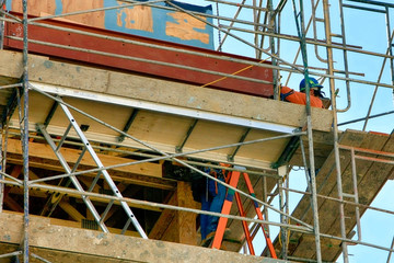 Two construction workers wearing safety equipment as they go about their jobs high up on...