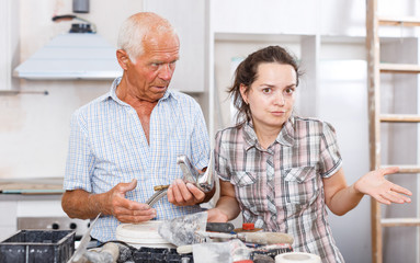 Perplexed woman and senior man with mixer tap
