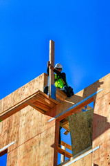 Construction worker wearing safety equipment as he goes about doing his job high up on scaffolding...