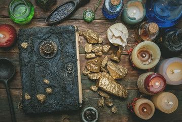 Golden stones and ancient magic book on alchemist table concept background.