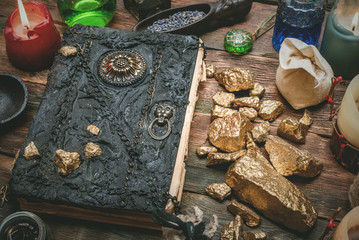 Golden stones and ancient magic book on alchemist table concept background.