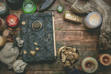 Golden stones and ancient magic book on alchemist table concept background.