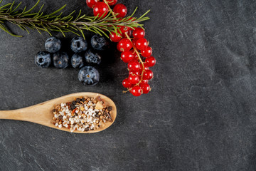 verschiedene zutaten wie blaubeeren, rosmarin und johannisbeeren auf einer schiefertafel 