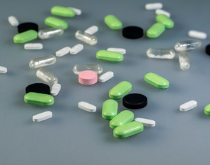 Tablets of various shapes and colors are scattered on a gray-blue surface.