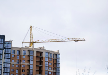 Crane and building construction site against blue sky. Metal construction of unfinished building on construction. Tower Crane use for building of multi storage building.