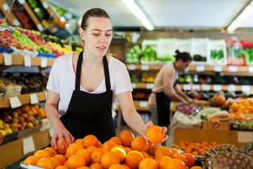 Obraz premium Young woman wearing apron working with fresh oranges