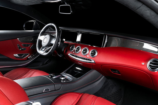 Red luxury modern car Interior with steering wheel, shift lever and dashboard. Clipping path. Detail of modern car interior. Automatic gear stick. Part of leather seats with stitching in expensive car