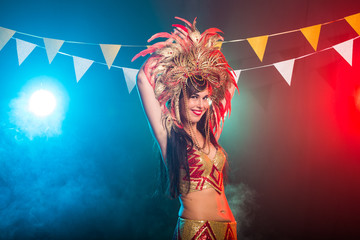 Fototapeta na wymiar Carnival, dancer and holiday concept - Beauty brunette woman in cabaret suit and headdress with natural feathers and rhinestones.