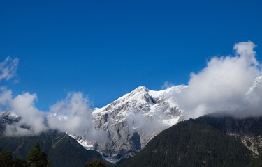 Mountain tops with snow, clouds, forest and blue cloudless sky, Wildermieming, Tirol, Austria