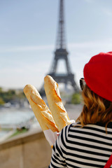 Woman standing with baguettes in Paris. Eiffel Tower in the background. French theme and vibes. 