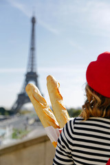 Woman standing with baguettes in Paris. Eiffel Tower in the background. French theme and vibes. 
