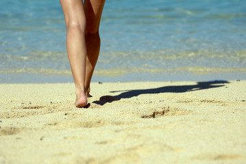 Walking on the beach. Close up on girl legs walking along the sea side.