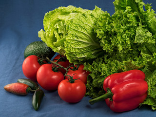 Green salad, Chinese cabbage, jalapenos, avocados, vegetables and fresh tomatoes on a blue textile background. Close-up. Selective focus on lettuce leaves. Horizontal orientation.