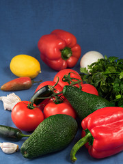 Fresh vegetables and fruits on a blue textile background. Close-up. Selective focus on avocado. Horizontal orientation.