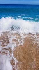 abstract background of sea waves, on golden sand, white sea foam, sunlight