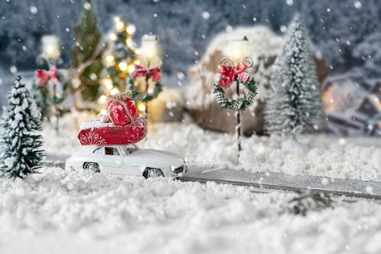 Miniature Classic Car Carrying A Christmas Gifts On Snowy Winter Landscape