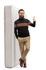 Bearded guy showing thumbs up and leaning on a mattress