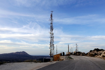 Telecommunications tower, antenna and satellite dish with blue sky at the top of the hill....